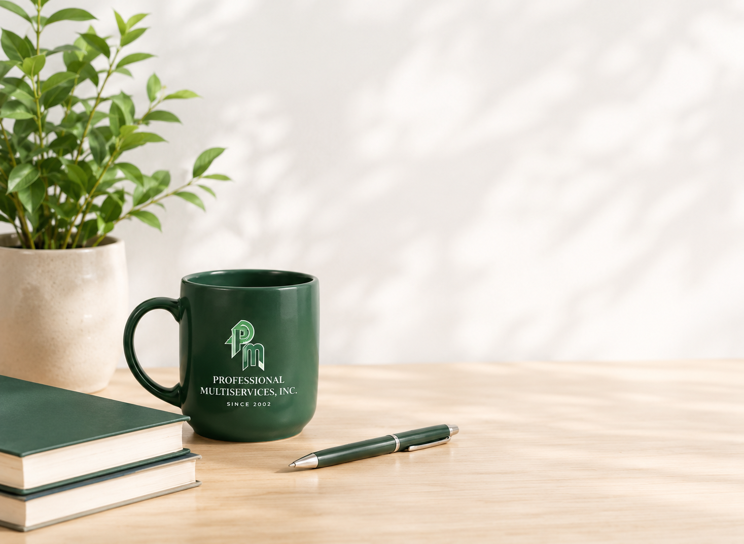 A Professional Multiservices branded mug on a desk beside a plant, stacked books, and a pen